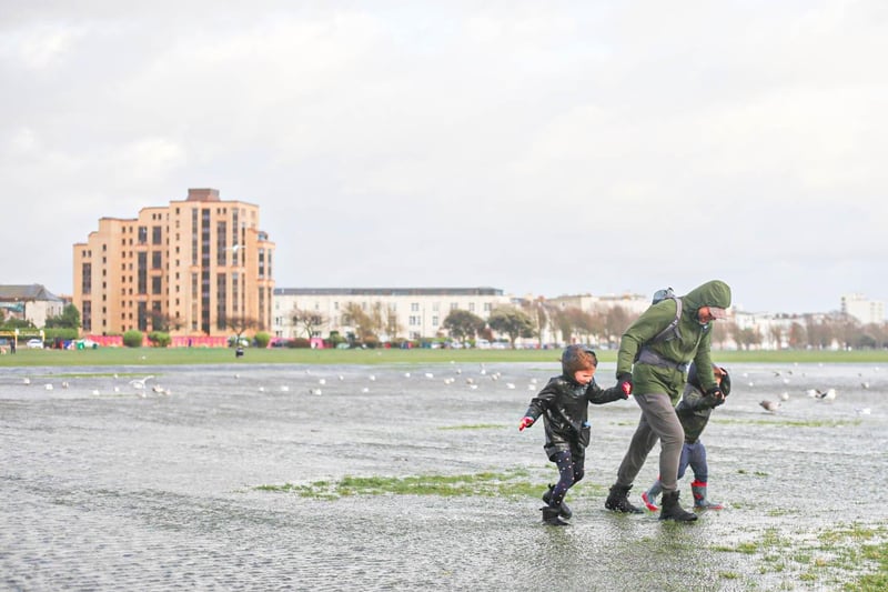 A family struggling against the wind in Southsea Common.