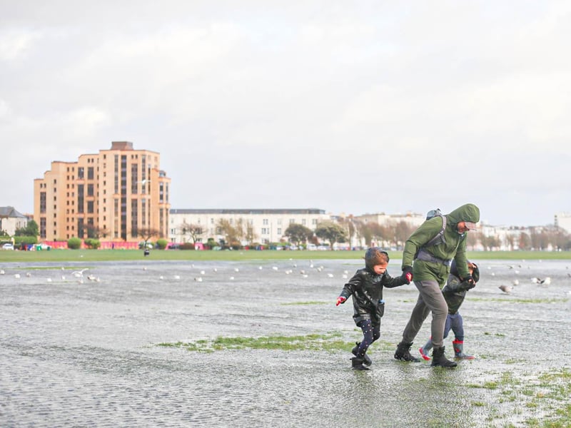 A family struggling against the wind in Southsea Common.