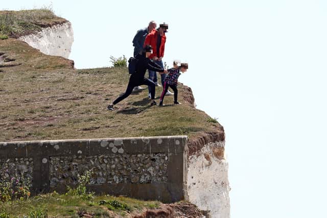 A young girl is held back as she peers over the edge of cliffs, which occasionally suffer cliff falls,  at Birling Gap. Picture: Gareth Fuller/PA Wire