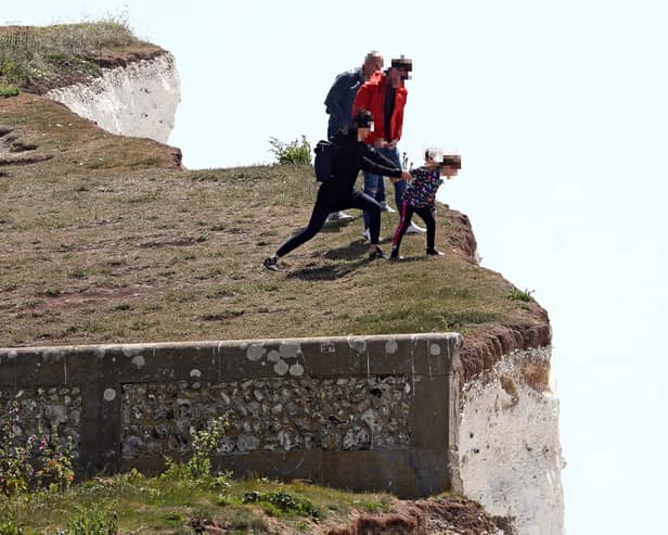 A young girl is held back as she peers over the edge of cliffs, which occasionally suffer cliff falls,  at Birling Gap. Picture: Gareth Fuller/PA Wire