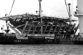 The Mary Rose in her cradle being brought ashore by barge in October 1982.
