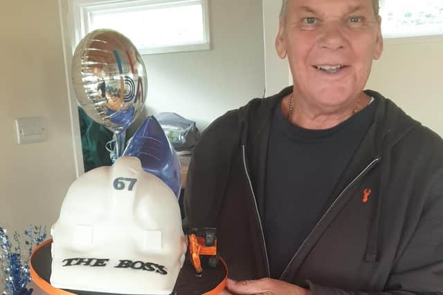 Graham holding a hard hat style birthday cake on his 67th birthday