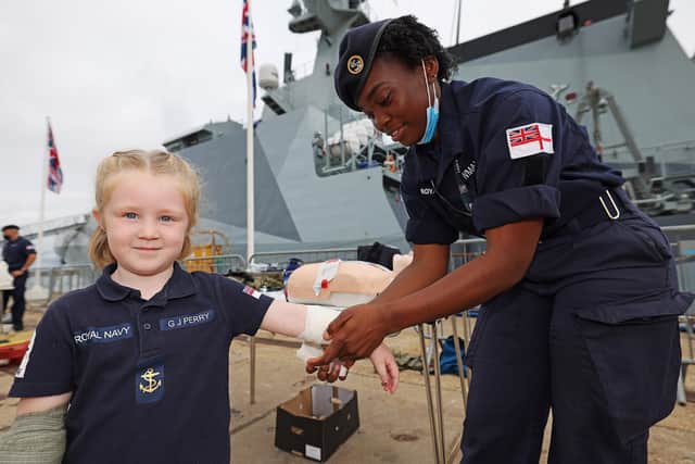 All patched up - a young girl has a bandage put on her by a member of HMS Spey's crew during the ship's families' day. Photo: LPhot Lee Blease