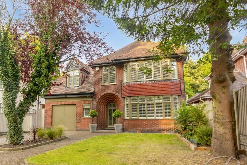 Nestled behind trees, the impressive facade of the Nottingham Road property. A spacious driveway offers ample off-street parking, while the lawn is low maintenance.