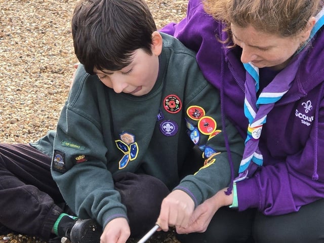 Jon (10) masters the art of using ferro rods to light a fire with the assistance of Skip, the Scout Team Leader.