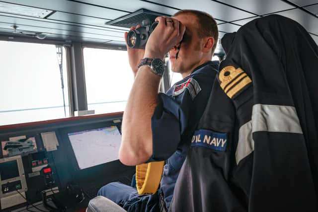 A Lieutenant Commanders uses a pair of binoculars to check out to sea on HMS Prince Wales