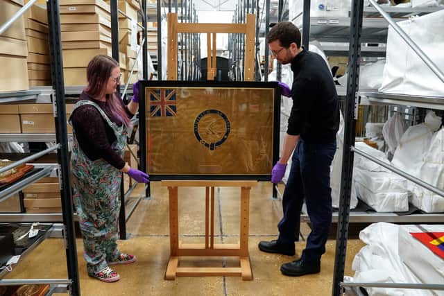 Conservators from the National Museum of the Royal Navy adjust the Kellet Sledge flag in it's frame at Portsmouth Historic Dockyard in Hampshire. Picture date: Wednesday May 16, 2023. Picture: Andrew Matthews/PA Wire