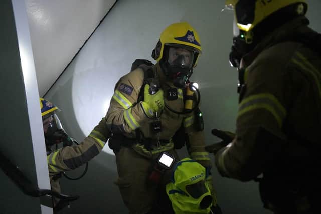 Firefighters working their way through a building while the officer in the centre carries one of the new, fluorescent smoke hoods designed to help evacuate people from blazing buildings. Photo: Hampshire and Isle of Wight Fire and Rescue Service.