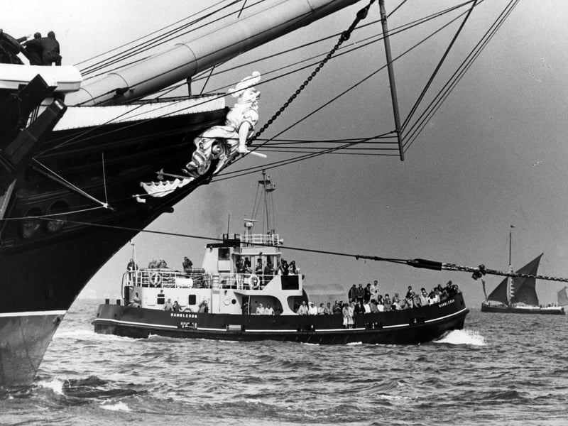 Sword in hand, Warrior's huge figurehead rides proudly above the welcoming craft, 1987. The News PP5392