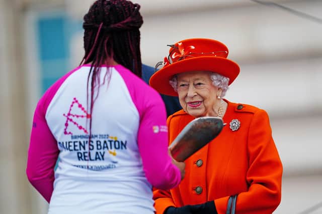 Queen Elizabeth II passes her baton to the baton bearer, British parasport athlete Kadeena Cox, during the launch of the Queen's Baton Relay for Birmingham 2022, the XXII Commonwealth Games at Buckingham Palace on October 7, 2021 in London, England. Photo by Victoria Jones - WPA Pool/Getty Images