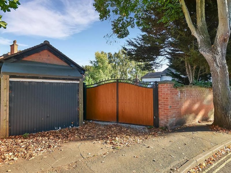 The electric gates off Terrace Road that lead to the parking area at the end of the back garden. Next to the driveway is a brick-built outbuilding.