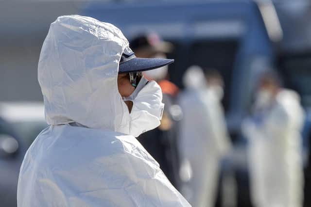 An Italian Red Cross' agent wearing protective suit and mask attends migrants rescued in the Mediterranean as they disembark from the Sea Watch NGO's ship on February 27, 2020 in the port of Messina, Sicily. Picture: Giovanni Isolino/AFP via Getty