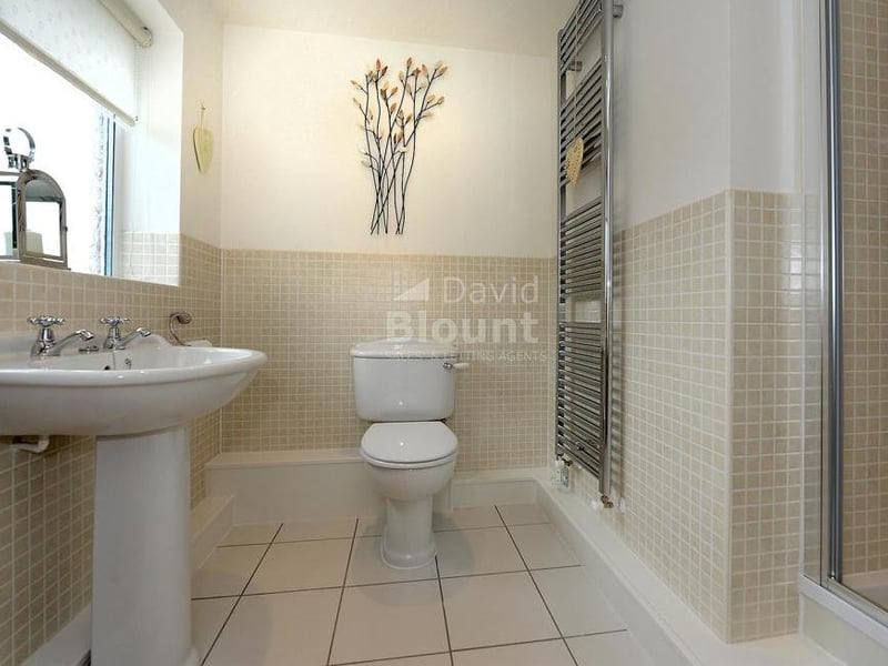 The en suite facilities to the second bedroom. They include a tiled shower-cubicle, wash hand basin, WC and upright chrome radiator.