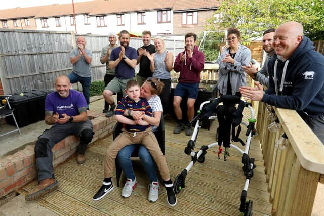 Archie Cleaver, 10, and his mother, Victoria Cleaver, have had their Paulsgrove garden made over by representatives from Propp, Glenhawk Finance, MT Finance, Together Finance and Helping Hands at Wellchild. They are pictured, centre, with, from front left, Kieran Cullen, Peter Turner, David Hounsell, Paul Elliott, Jamie Pritchard, Sally Precious Ward, Ben Larkin, Harriet King, Richard Sherman and Pete Williams. Picture: Chris Moorhouse (jpns 040522-42)