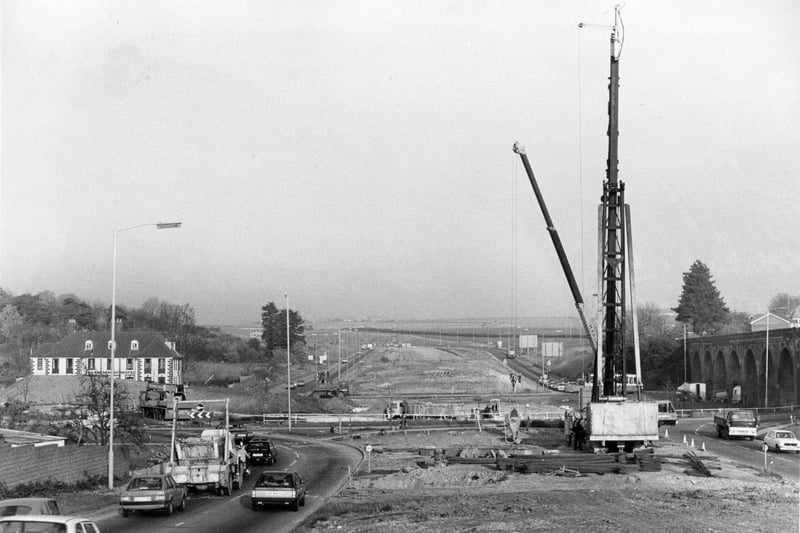 A view of the work in progress on the Delme Roundabout Flyover, showing the giant pile-driver in position and the route that the road will take in November 1983. The News PP987