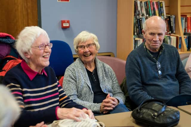 Three people with sight loss smiling as they attend their local Macular Society support group, which is in need of volunteers in Waterlooville.