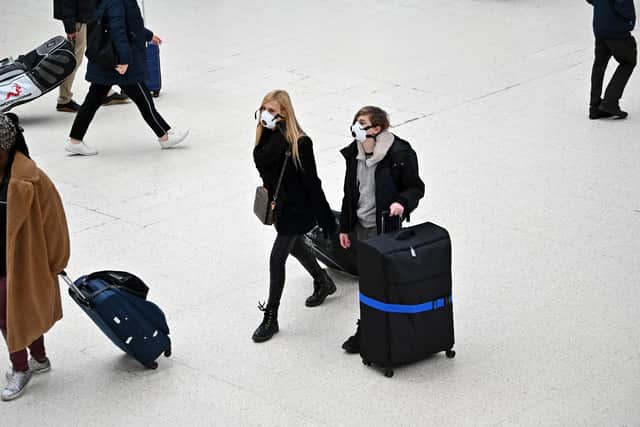 Travellers wearing protective face masks pull their suitcases while walking across the concourse at London Victoria train station. Picture: JUSTIN TALLIS/AFP via Getty Images
