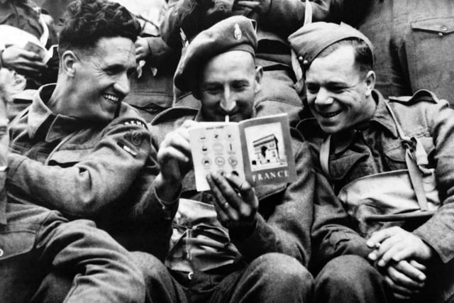 June 1944 of British soldiers joking as they read a tourist guide about France aboard a landing craft while Allied forces storm the Normandy beaches on D-Day. D-Day, 06 June 1944 is still one of the world's most gut-wrenching and consequential battles, as the Allied landing in Normandy led to the liberation of France which marked the turning point in the Western theater of World War II.  (Photo credit should read -/AFP/Getty Images)