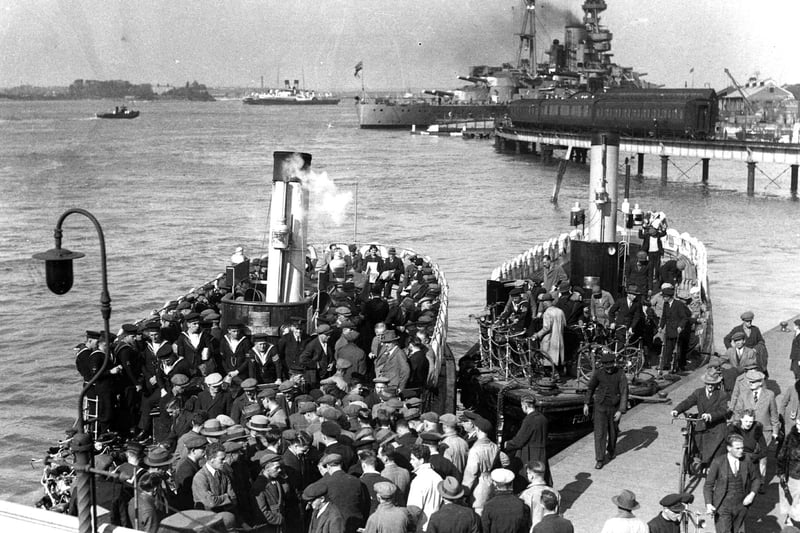 Hordes of dockyard workers, sailors and commuters caught boarding and alighting two Gosport ferries in 1936. A battleship behind the train and to the left is a paddle steamer. Picture: Courtesy Sid Greeman.