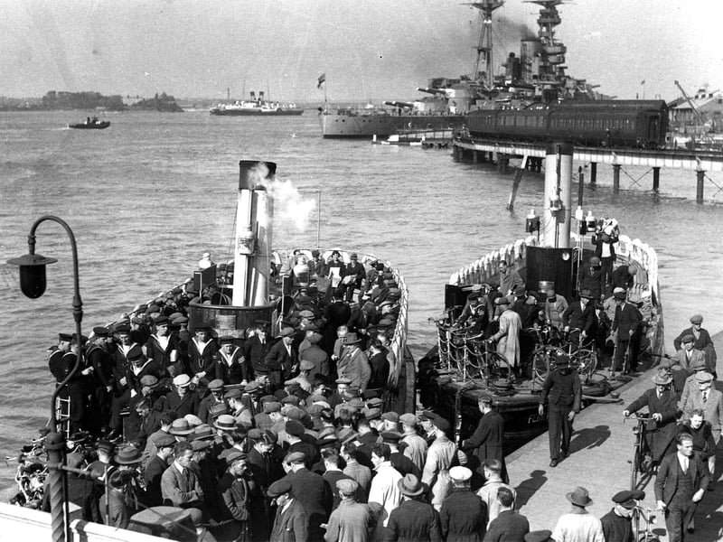 Hordes of dockyard workers, sailors and commuters caught boarding and alighting two Gosport ferries in 1936. A battleship behind the train and to the left is a paddle steamer. Picture: Courtesy Sid Greeman.