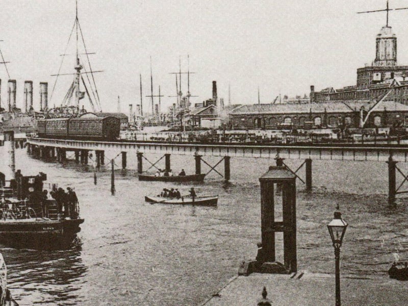 A view of the dockyard about 1908 with Gosport ferries in the foreground. The railway line opened in 1876. It was built as part of the harbour extension across the foreshore of Watering Island. The jetty here was constructed in 1860 and was especially suitable for troopships