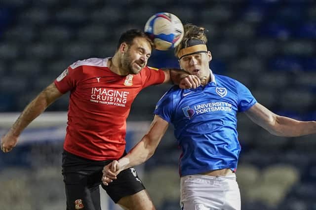 Sean Raggett of Portsmouth heads the ball under pressure from, Brett Pitman of Swindon Town during the EFL Sky Bet League 1 match between Portsmouth and Swindon Town at Fratton Park, Portsmouth, England on 9 February 2021.