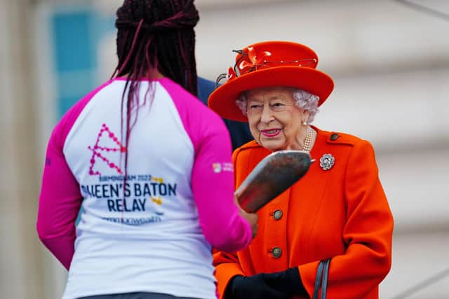 Queen Elizabeth II passes her baton to the baton bearer, British parasport athlete Kadeena Cox, during the launch of the Queen's Baton Relay for Birmingham 2022, the XXII Commonwealth Games on October 7, 2021 in London, England. photo by Victoria Jones - WPA Pool/Getty Images