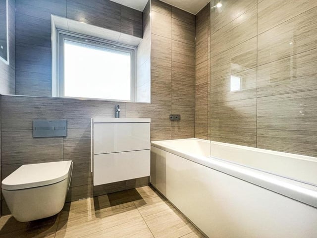 The listing says: "Moving to the second floor, the property is completed with a primary suite featuring spacious landing space with built in wardrobes with access into the large double bedroom which has a south facing Juliette balcony. The top floor is completed by a large bathroom with double sinks, vanity mirrors, a freestanding bath, separate shower cubicle and marble effect tiles."