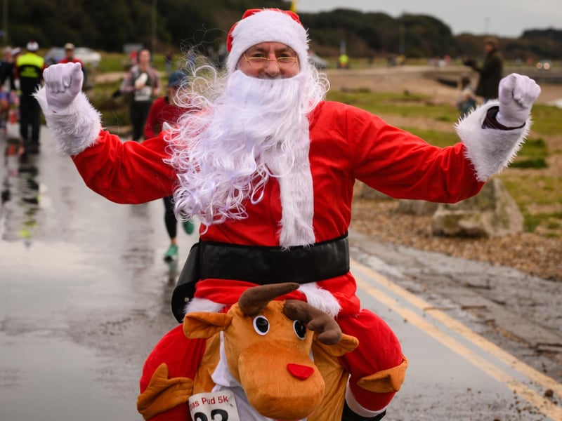 Stuart Wood celebrates crossing the finishing line in his Santa and Rudolph costume at the Christmas Pud 5k, Stokes Bay, Gosport