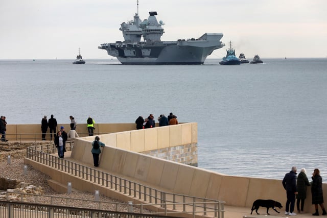HMS Queen Elizabeth approaches the newly reopened walkway on the sea defences at Long Curtain Moat, as she returns to Portsmouth Naval Base.