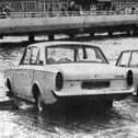 Two cars about to be overcome by the tide on the slipway at the  Hard in 1970. The new approach road from the Hard to the Harbour Station can be seen in the background.