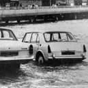 Two cars about to be overcome by the tide on the slipway at the  Hard in 1970. The new approach road from the Hard to the Harbour Station can be seen in the background.