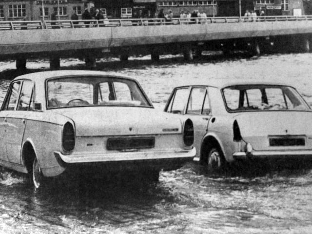 Two cars about to be overcome by the tide on the slipway at the  Hard in 1970. The new approach road from the Hard to the Harbour Station can be seen in the background.