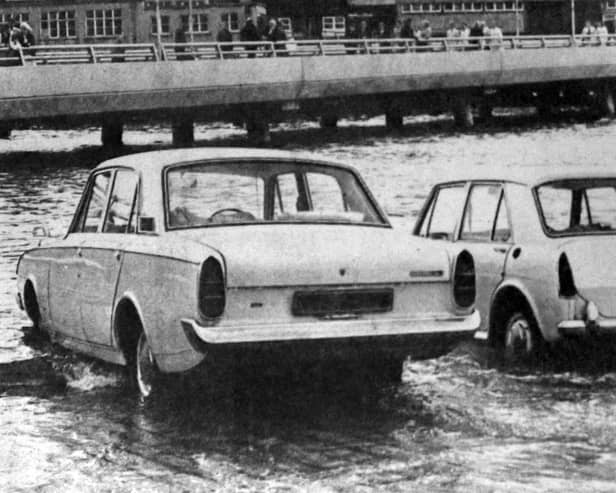 Two cars about to be overcome by the tide on the slipway at the  Hard in 1970. The new approach road from the Hard to the Harbour Station can be seen in the background.