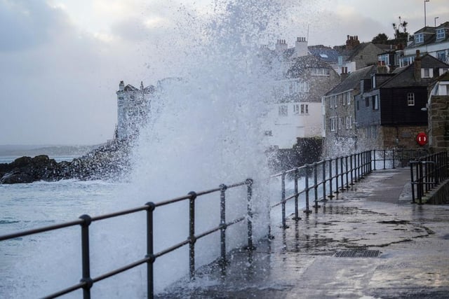 A wave breaks over a path way on the harbour of St Ives which missed the worst of Friday morning's weather. (Photo by Hugh Hastings/Getty Images)