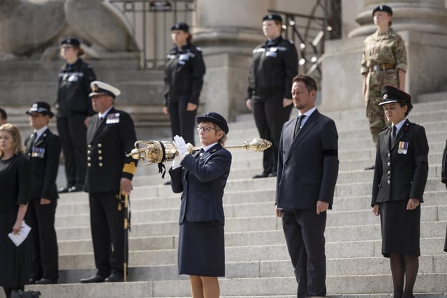 Officials and personnel close their eyes to pay their respects to the Queen.