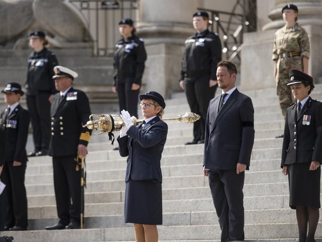 Officials and personnel close their eyes to pay their respects to the Queen.
