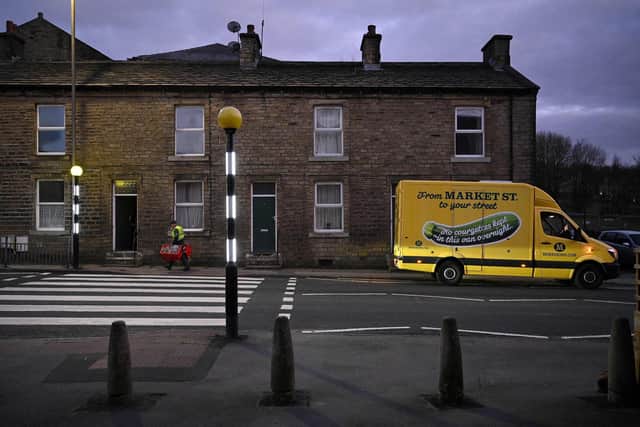 A delivery driver carries baskets of food as he delivers an online shopping order to a resident, from the supermarket Morrisons. Picture: OLI SCARFF/AFP via Getty Images