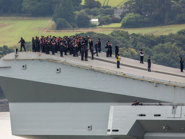 HMS Queen Elizabeth passes under the Forth Bridge as she heads back to sea following lengthy time at Rosyth for repairs and upgrades due to mechanical fault. July 22, 2024.
