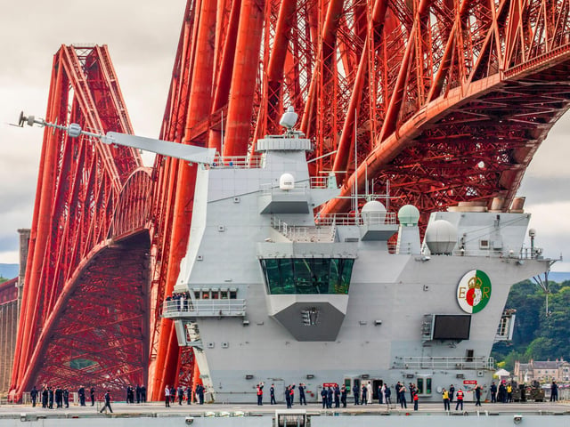 HMS Queen Elizabeth passes under the Forth Bridge as she heads back to sea following lengthy time at Rosyth for repairs and upgrades due to mechanical fault. July 22, 2024.