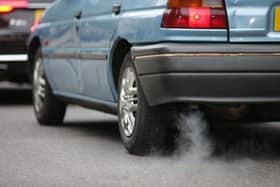 A car emits fumes from its exhaust as it waits in traffic