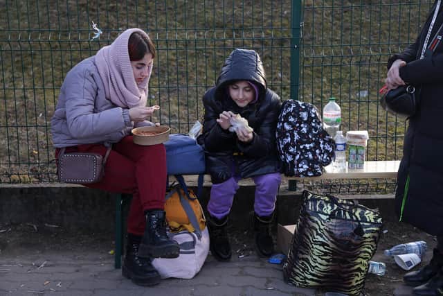 Two sisters who had just arrived with their mother from war-torn Ukraine eat food at an aid station at the Medyka border crossing on March 15, 2022 in Medyka, Poland. Photo by Sean Gallup/Getty Images.