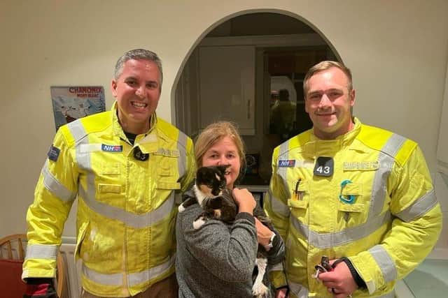 Holly the cat was rescued by firefighters after getting her claws stuck in a patio table. 
Pictured: Holly with her owner and the firefighters.