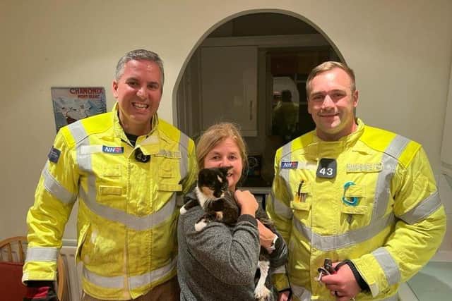 Holly the cat was rescued by firefighters after getting her claws stuck in a patio table.
Pictured: Holly with her owner and the firefighters.