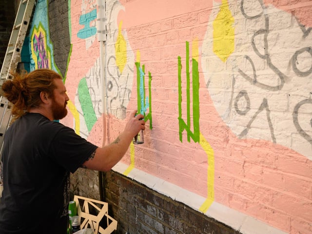 Pictured is: Mank at work on his mural, one of many artworks along the railway arches by the Hard.  Picture: Keith Woodland (140921-108)
