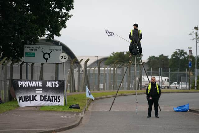A Extinction Rebellion activist protests on top of a structure outside Farnborough Airport in Hampshire in protest against emissions from private jets. Picture date: Saturday October 2, 2021. PA Photo. See PA story ENVIRONMENT Airport. Photo credit should read: Andrew Matthews/PA Wire