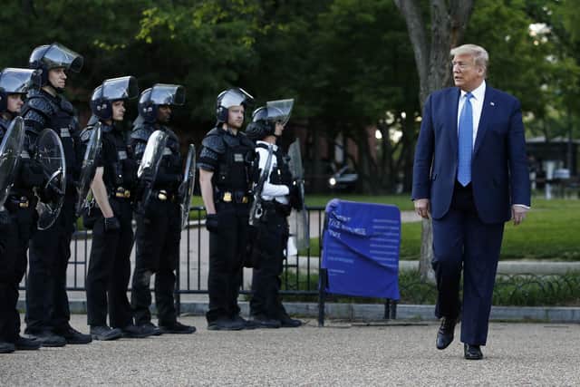 President Donald Trump walks past police in Lafayette Park after visiting outside St. John's Church across from the White House Monday, June 1, 2020, in Washington. Part of the church was set on fire during protests on Sunday night. (AP Photo/Patrick Semansky)