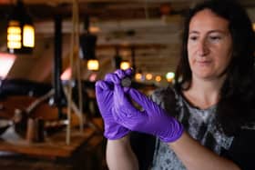 Diana Davis, head of conservation at the National Museum of the Royal Navy, holds a 127-year-old farthing on the gun deck of HMS Victory after it was found under the main mast of the ship when it was removed earlier this year as part of a 20-year-long conservation project. Photo: Andrew Matthews/PA Wire