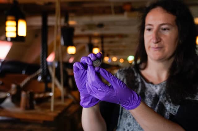 Diana Davis, head of conservation at the National Museum of the Royal Navy, holds a 127-year-old farthing on the gun deck of HMS Victory after it was found under the main mast of the ship when it was removed earlier this year as part of a 20-year-long conservation project. Photo: Andrew Matthews/PA Wire