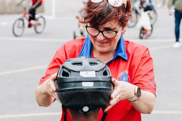 Pedal Power Training Director, Donna Coyne helping a young cyclist fit his cycling helmet (Buckland Community Day, 26 July, 2025)